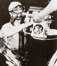 Jacques-Yves Cousteau s’apprête à plonger avec  un appareil photo de prise de vue sous-marine