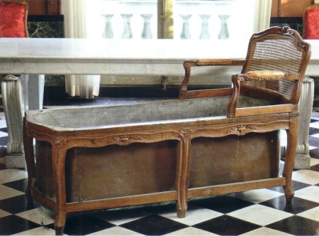 Baignoire dissimulée par une chaise longue en bois.