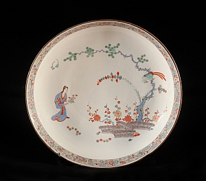 Plat rond (vers 1730-1735) où est figurée une femme en kimono tenant un bouquet de fleurs sous un pin, sur lequel est posé un oiseau.  Inv. OA 1033, Chantilly – musée Condé